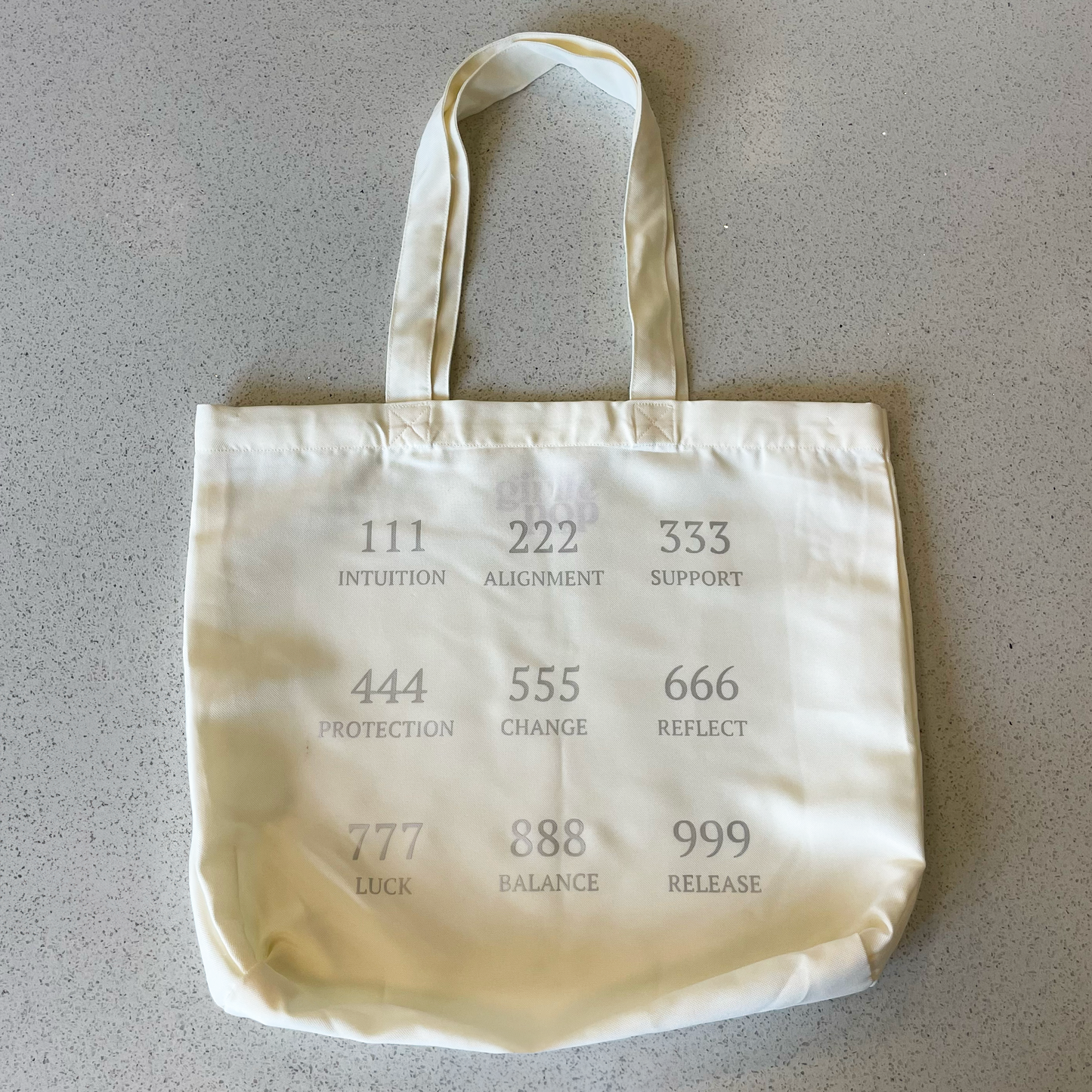 tote bag on a table with the angel numbers in silver