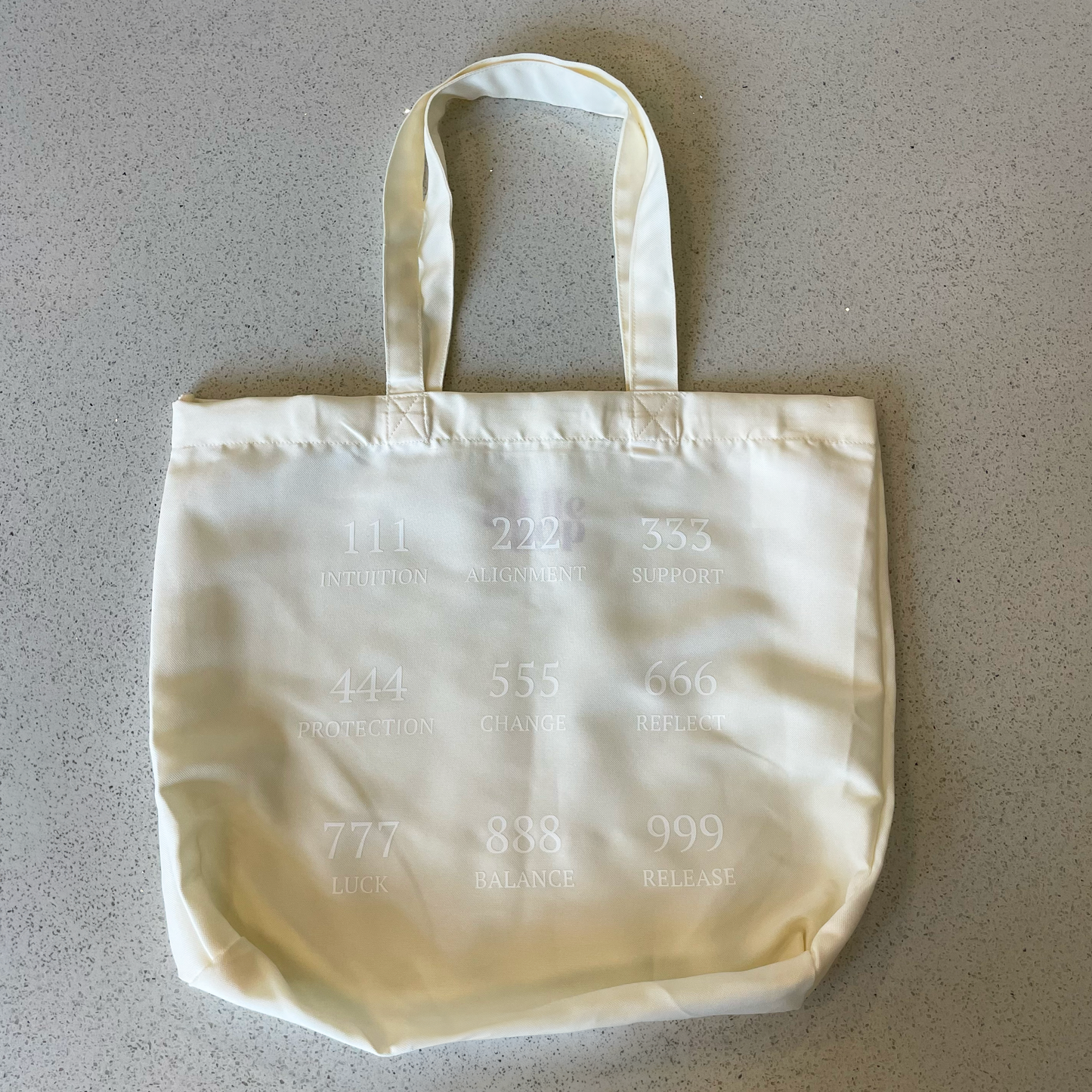 tote bag on a table with the angel numbers in white
