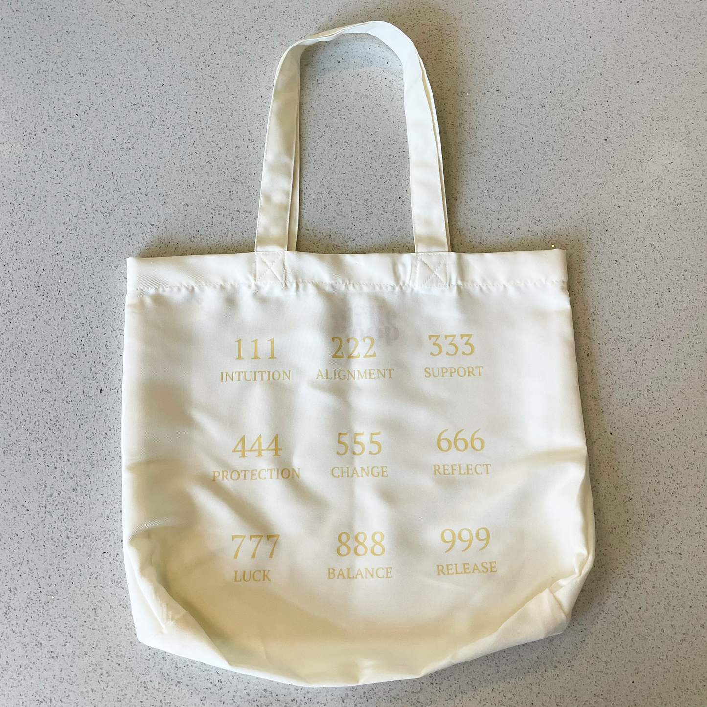 tote bag on a table with the angel numbers in beige