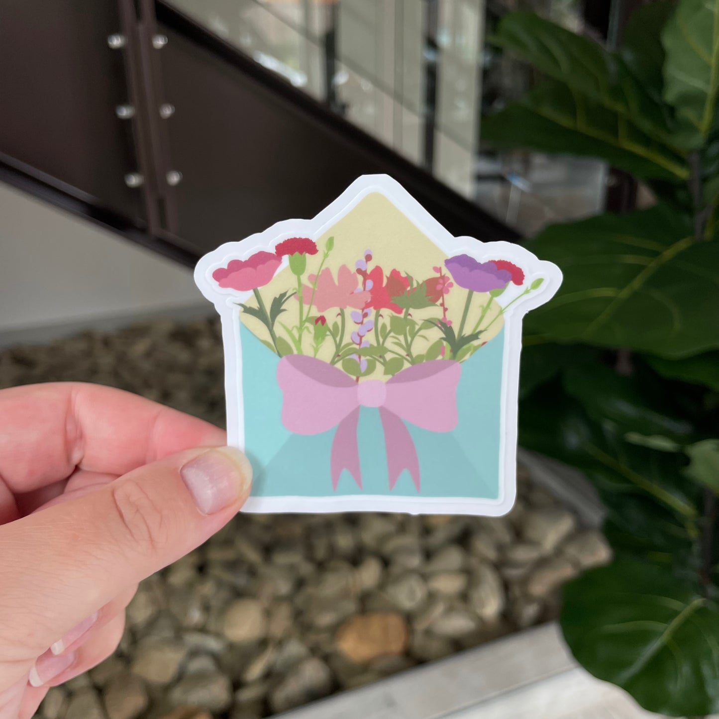 blue envelope filled with flowers and tied with a pink bow
