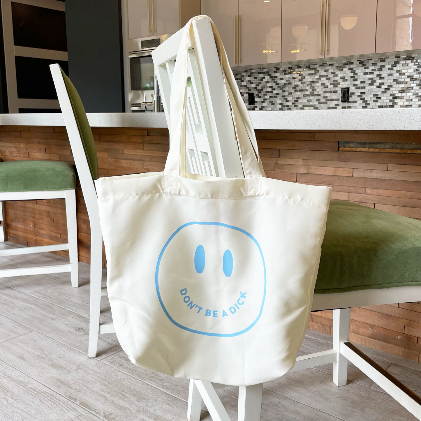 light blue don't be a dick tote bag hanging from a chair
