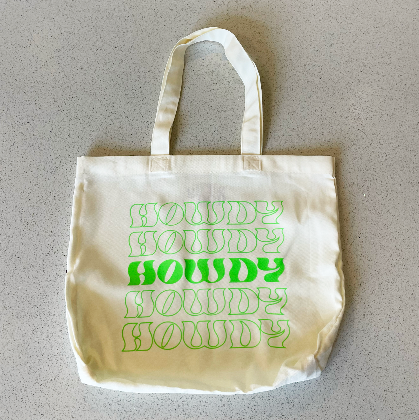 tote bag that says howdy in neon green