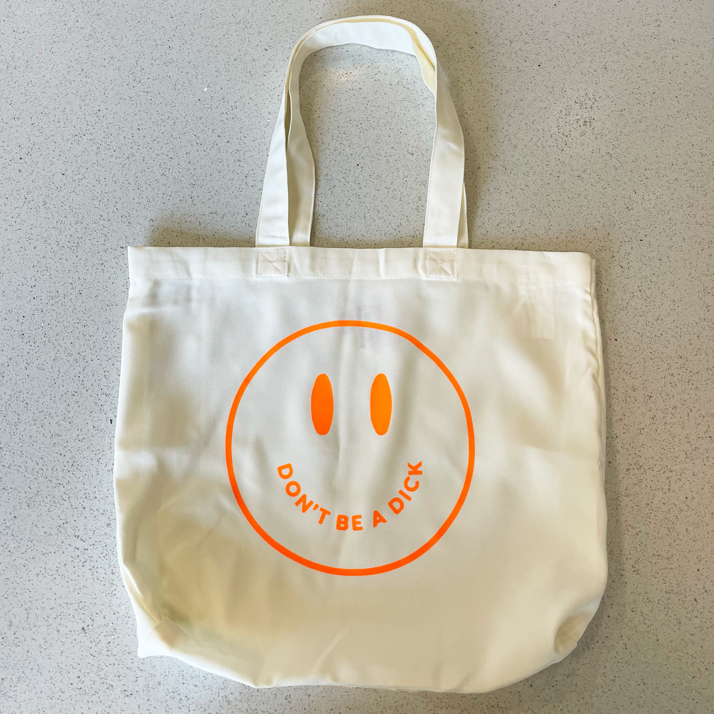 tote bag with neon orange smiley face saying don't be a dick