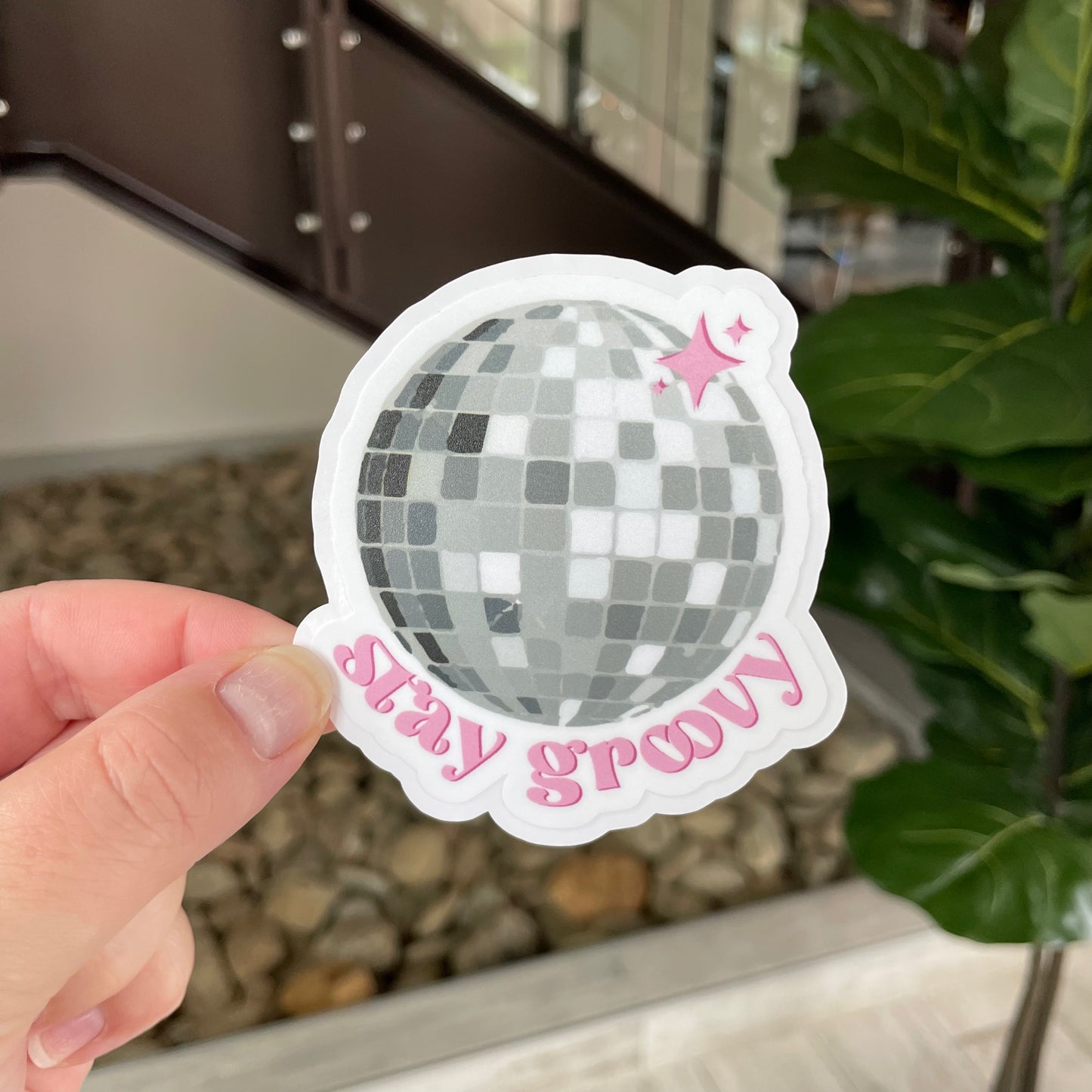 disco ball with sparkles and pink writing saying stay groovy
