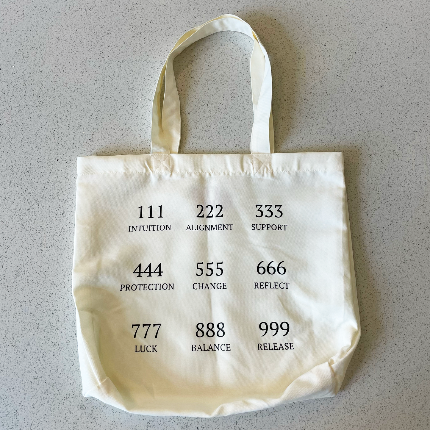 tote bag on a table with the angel numbers in black