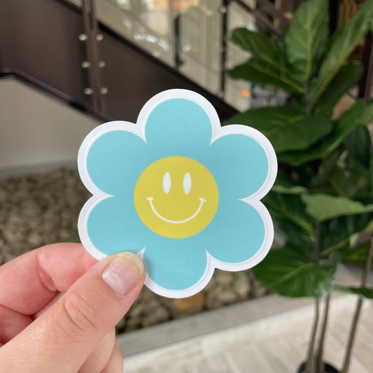 hand holding blue smiley face flower sticker