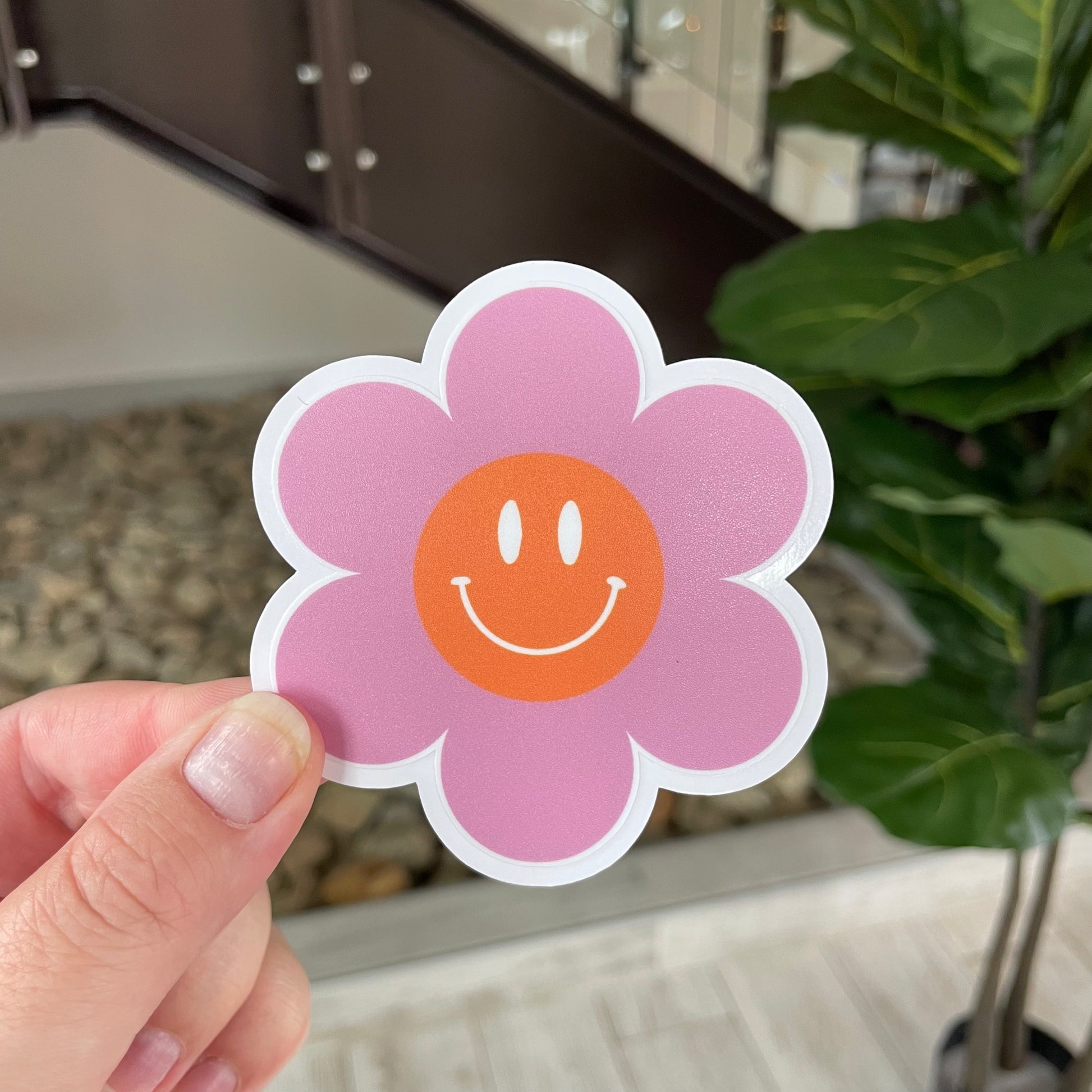 hand holding pink smiley flower sticker