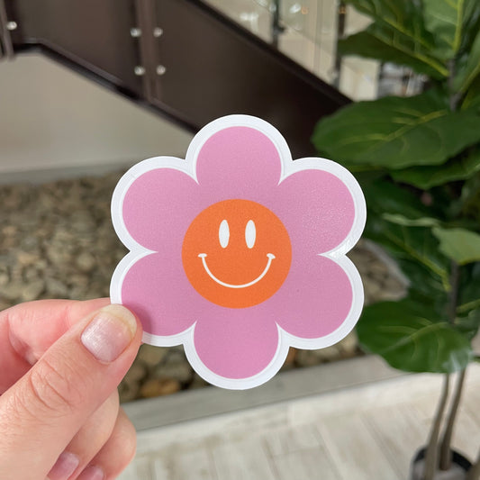 hand holding pink smiley flower sticker