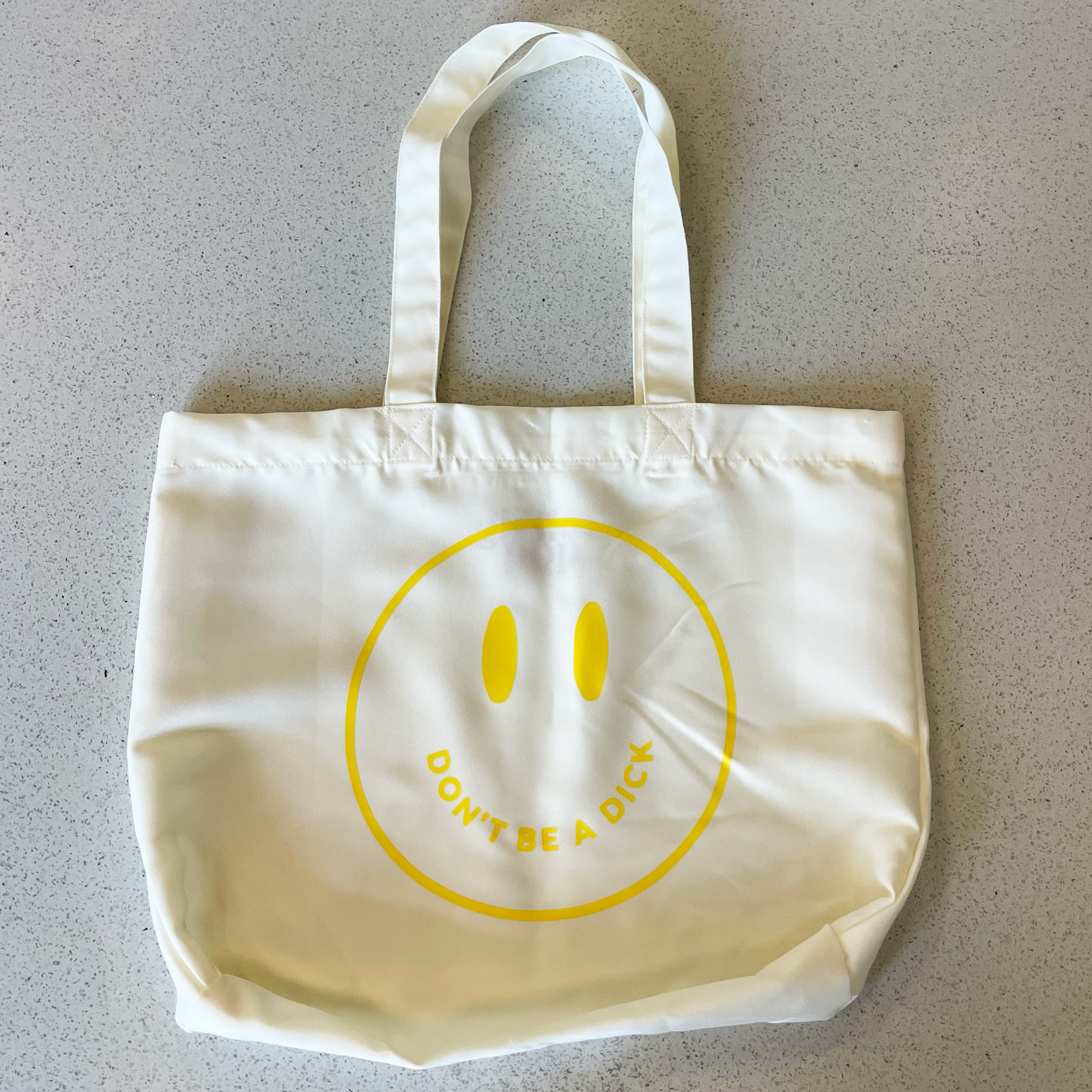 tote bag with yellow smiley face saying don't be a dick